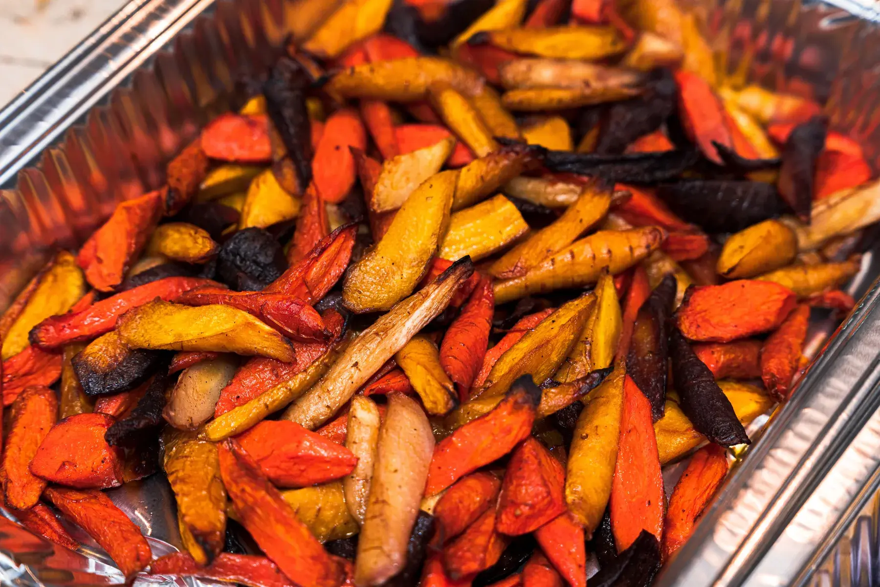 Roasted root vegetables in a catering pan prepared by Dragonfly Catering