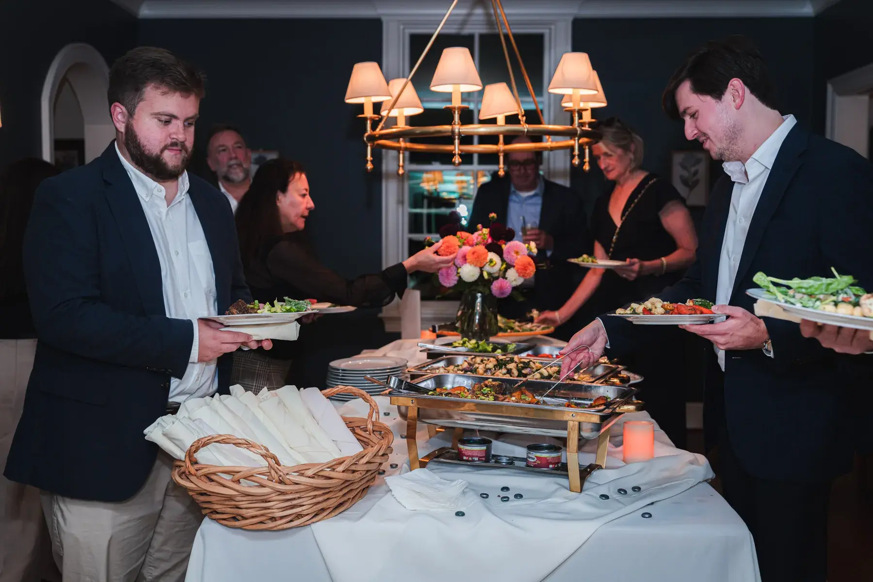 Guests choosing dishes from a Dragonfly Catering buffet at an evening event