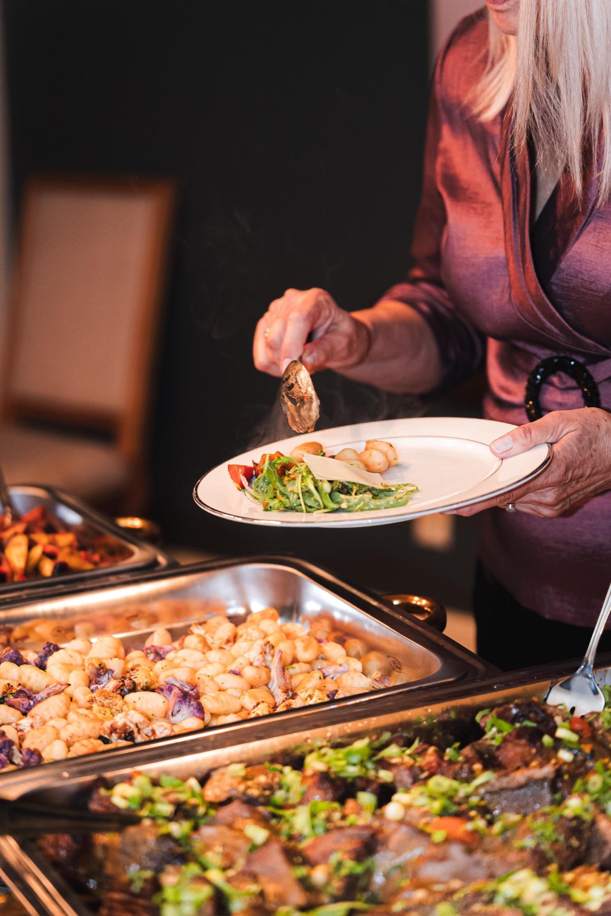 A guest serving dinner from a Dragonfly Catering buffet at an engagement party