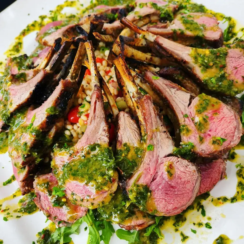 Sliced rack of lamb with herb sauce prepared by Dragonfly Catering