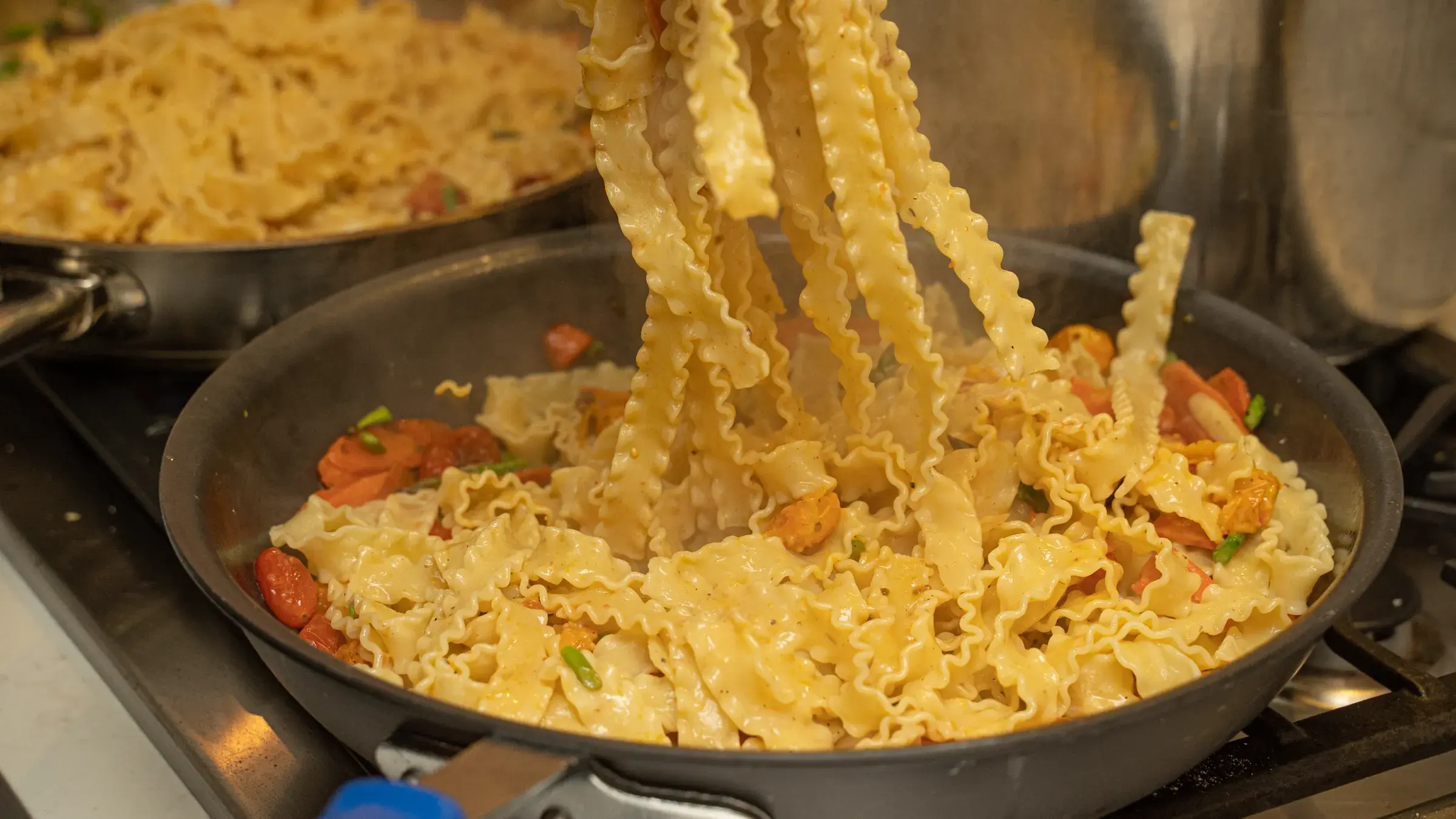 Fresh pasta being prepared in saute pans during Dragonfly Catering event prep